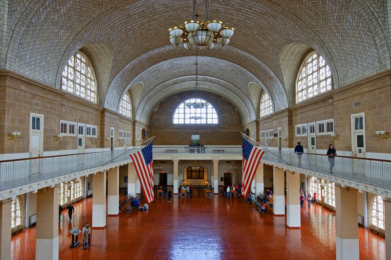 Great Hall has terra cotta-colored tile floor, a balcony, large arched windows, and vaulted ceiling