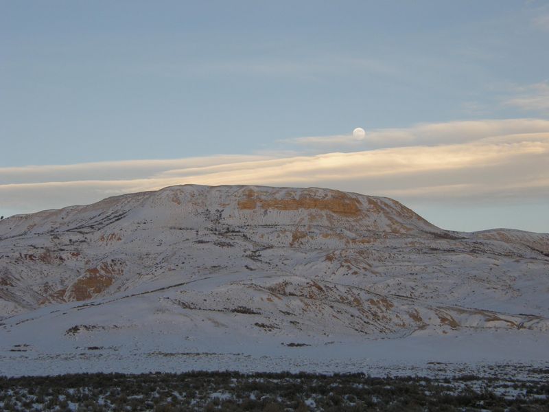 The moon over a snow-covered butte