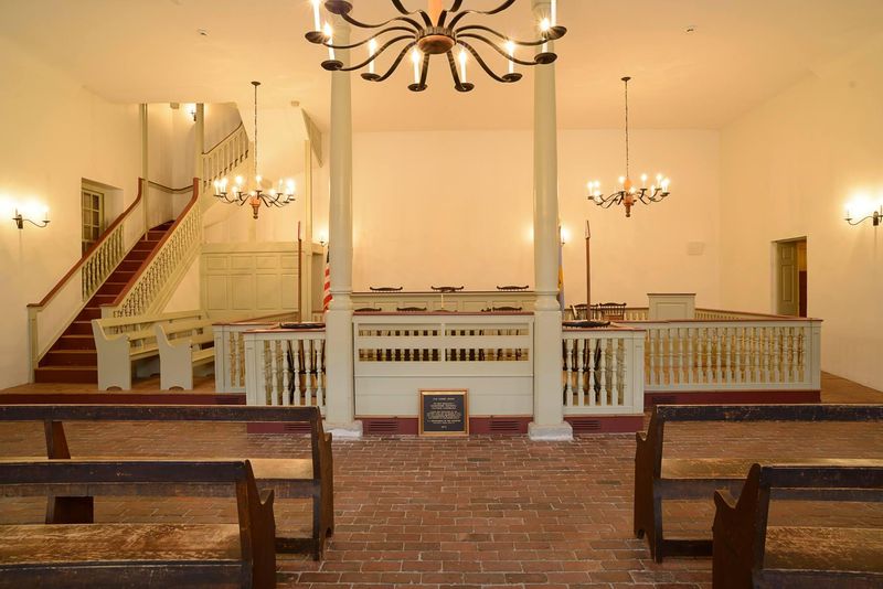 Pews line the side of the room leading to the English style court room.