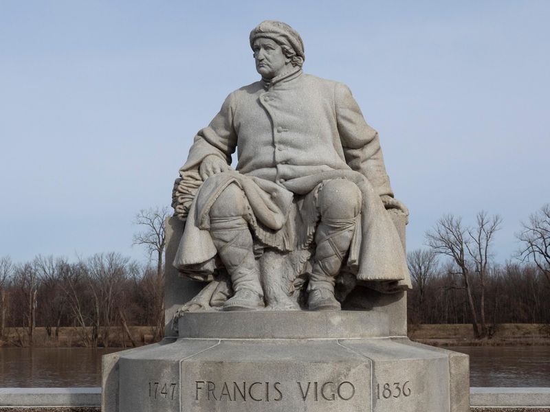 A granite statue of Francis Vigo, seated, dressed in 18th century fur trader clothing