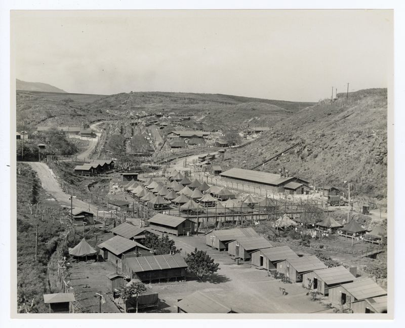 A historic photo of a valley filled with tents and wooden buildings