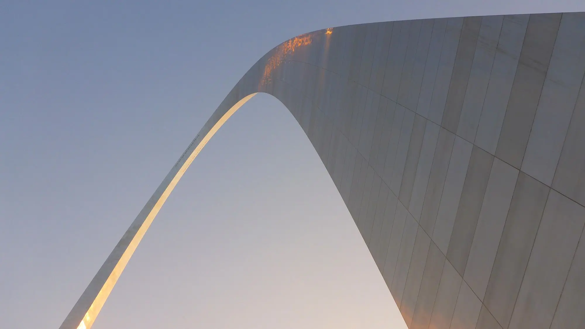 looking up at the curve of the Gateway Arch against the sky