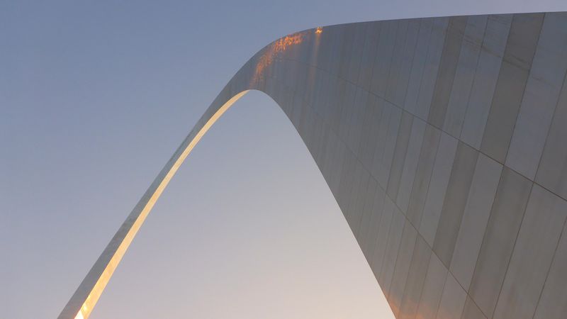 looking up at the curve of the Gateway Arch against the sky