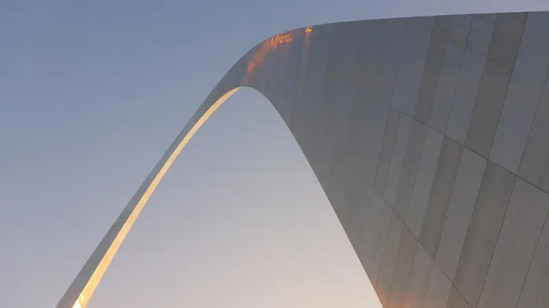 looking up at the curve of the Gateway Arch against the sky