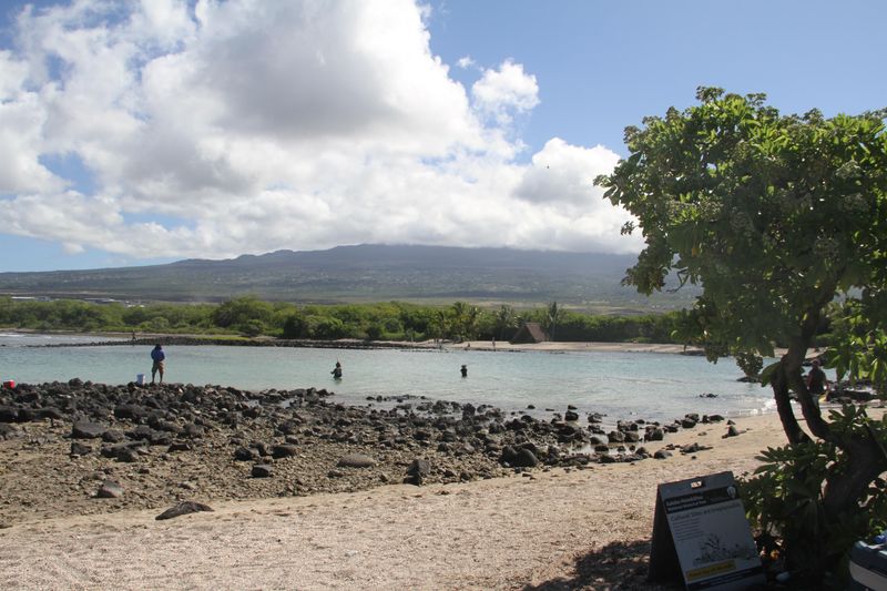 White sand beach at the base of a large volcano.
