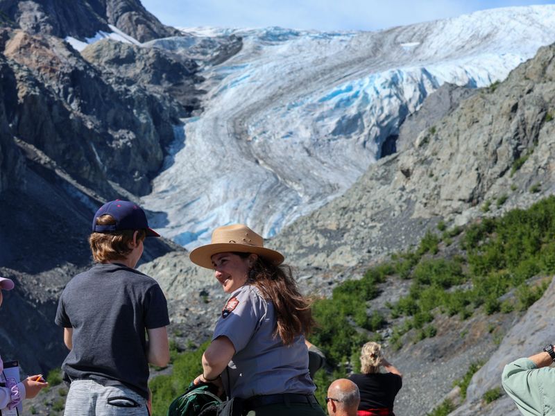 A park ranger talks with a child with Exit Glacier in the background