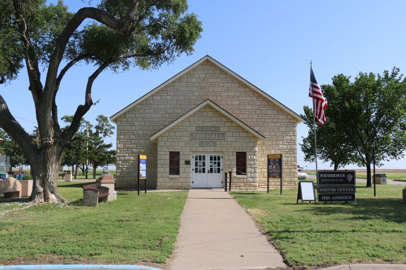A limestone brick building with grass and trees around it