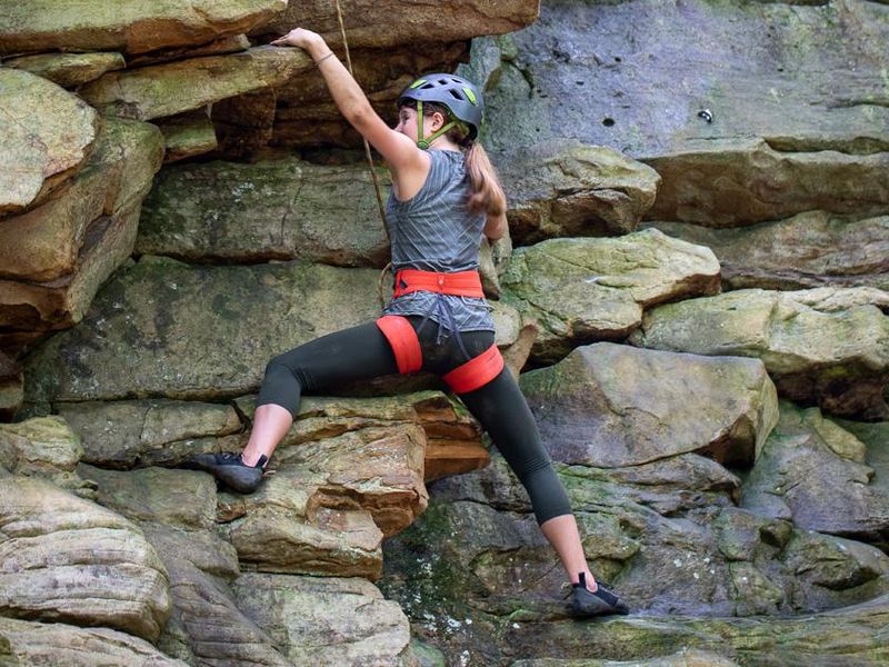 A female rock climbing on the face of a rock wall.