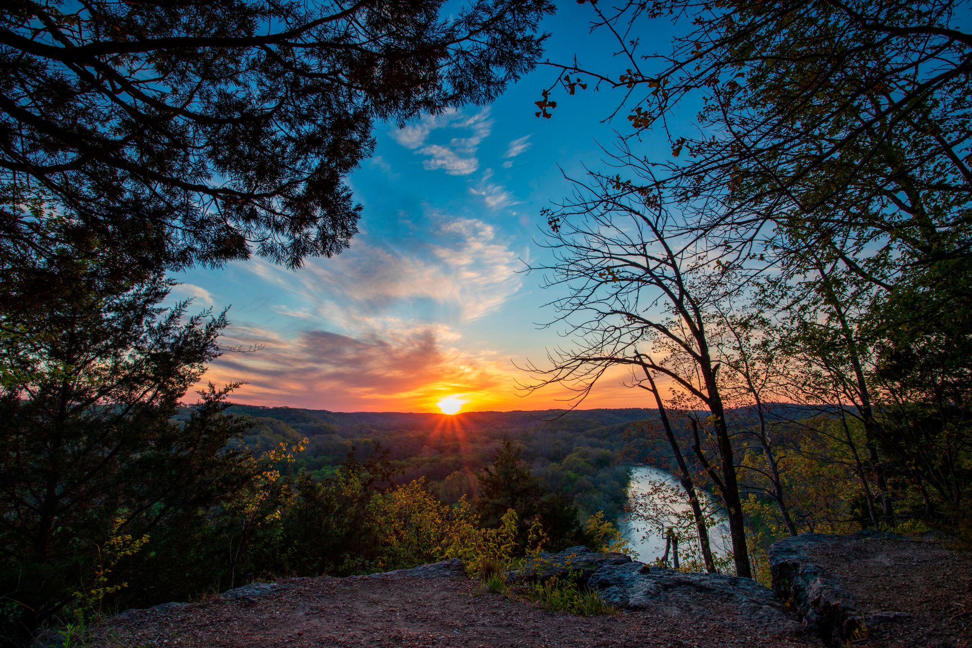 Sunset picture with high vantage point overlooking river with fall colors and sun setting in distanc