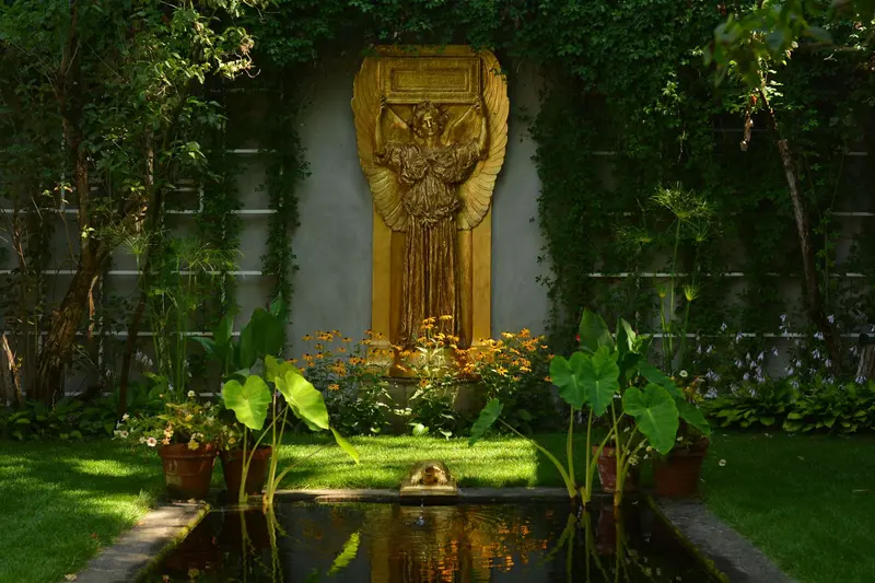 gilded statue of angel with plants and reflecting pool