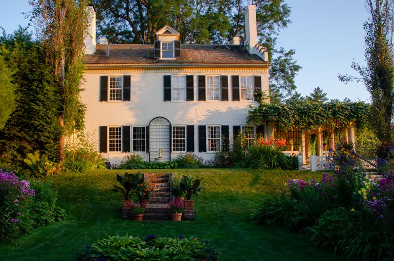 historic white brick house with flower gardens